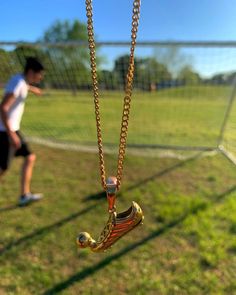 a man is playing with a soccer ball in the background and a gold necklace hanging from it's end