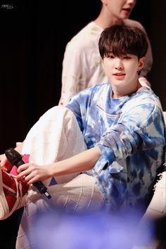 a young boy sitting on top of a white couch next to another person holding a remote control