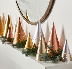 a row of christmas trees sitting on top of a white shelf next to a mirror