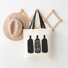 a tote bag with two bottles on it next to a hat and wall hooks