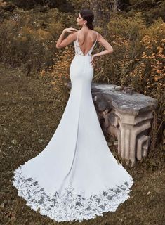 a woman in a white wedding dress standing next to a stone bench