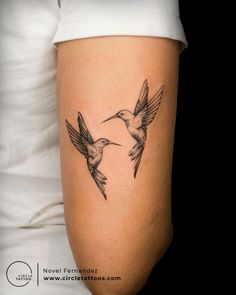 a woman's arm with two hummingbirds flying in the air and one on her left side