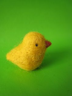 a small yellow bird sitting on top of a green surface