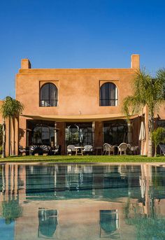 a large house with a pool in front of it and palm trees around the pool