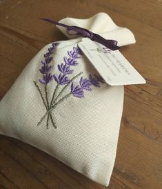 a purple flower on a white cloth bag with a tag attached to the end of it