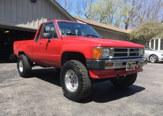 a red pick up truck parked in front of a garage