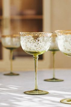 three wine glasses sitting on top of a table next to each other with white flowers in them