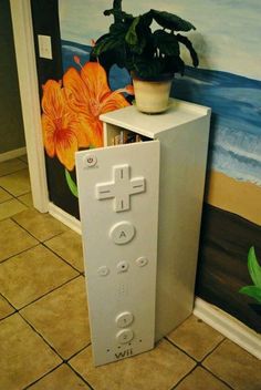 a nintendo wii game controller sitting on top of a cabinet next to a potted plant