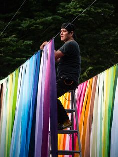 a man standing on a ladder next to rainbow colored streamers