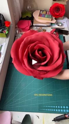 a rose being made on a cutting board with scissors and other crafting supplies around it