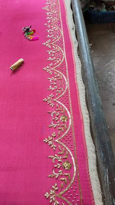 a pink table cloth with gold trimmings and beads on the edge, next to a bottle of wine