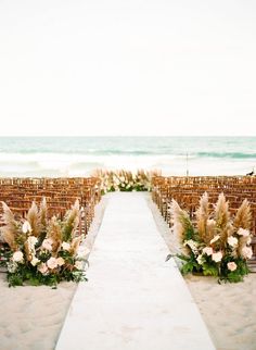 the aisle is decorated with flowers and pamodia for an outdoor ceremony at the beach