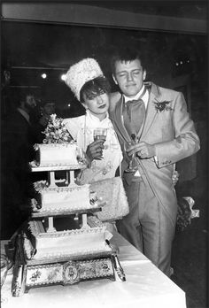 an old black and white photo of a man and child standing in front of a cake