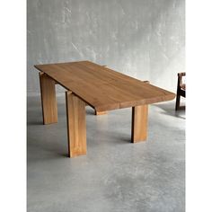 a wooden table sitting on top of a cement floor next to a chair and wall