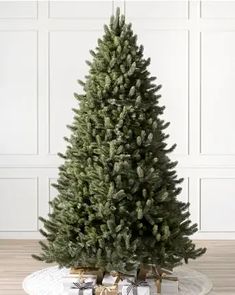 a small christmas tree sitting on top of a glass table next to a white wall