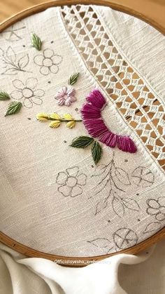 a close up of a embroidery on a piece of cloth with flowers in the middle