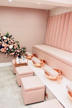 a room with pink furniture and flowers on the wall, along with two benches that have gold trim around them