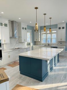 a large kitchen with blue cabinets and white counter tops, an island in the middle