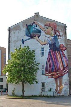 a large mural on the side of a building with a girl holding a watering can