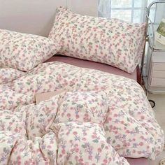 an unmade bed with pink and white floral comforter, pillows and pillow cases