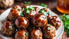 a white plate topped with meatballs covered in sauce and garnished with parsley