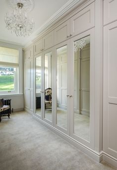 a large white closet with mirrored doors and chandelier