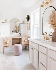 a white bathroom with gold accents and mirrors on the wall, along with a pink stool