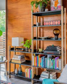 a bookshelf filled with lots of books in a living room next to a window