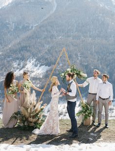 a group of people standing next to each other in front of snow covered mountains and trees