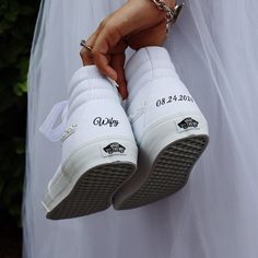 the bride is holding her wedding shoes with their names on them and they are wearing white slippers