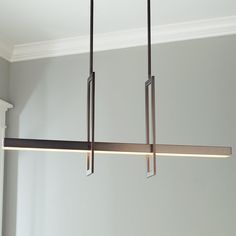 a modern light fixture hanging from the ceiling in a room with gray walls and white trim