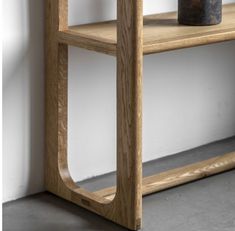 a wooden shelf with a vase sitting on it's side next to a wall