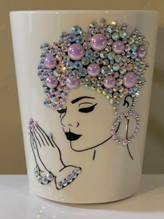 a white cup with a woman's face painted on it and beaded decorations