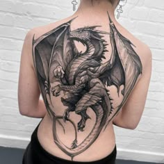 a woman's back with a dragon tattoo on it