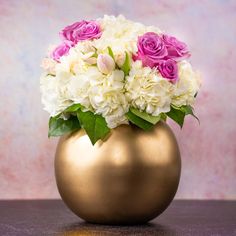 a gold vase filled with white and pink flowers