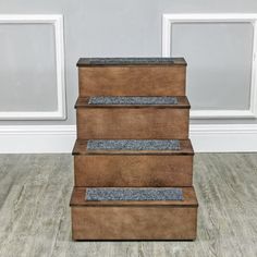 a set of three brown leather steps sitting on top of a hard wood floor next to a white wall