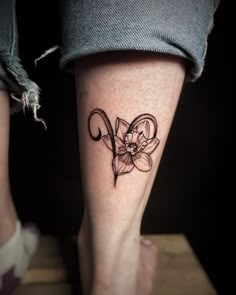 a woman's foot with a flower tattoo on her left leg and the word love written in cursive writing