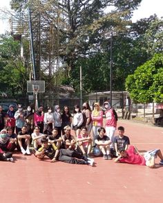 a group of people standing and sitting on top of a basketball court next to each other