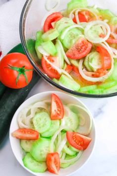 two bowls filled with cucumbers and tomatoes on top of a white countertop