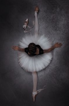 a ballerina in white tutu and black leotard with her arms stretched out