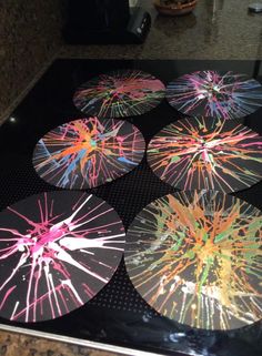 four coasters with colorful fireworks on them sitting on a stove top in a kitchen