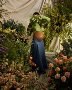 a pregnant woman is surrounded by flowers and greenery