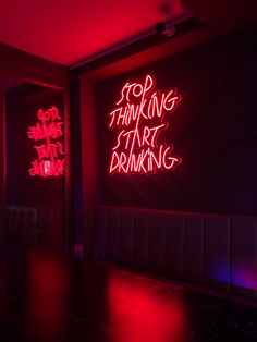 two red neon signs on the wall in a dark room with black floors and walls