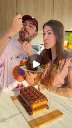 a man and woman sitting at a table eating cake with spoons in front of them