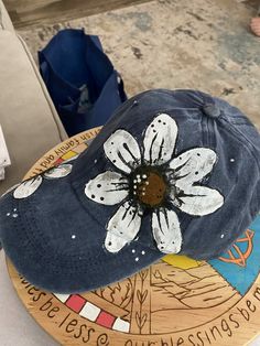 a blue hat with a white flower on it sitting on top of a wooden plate