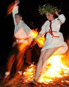 two women dressed in white dancing around a fire