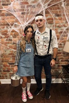 a man and woman dressed in costumes standing next to a brick wall with spider webs on it