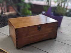 a wooden box sitting on top of a wooden table next to potted planters