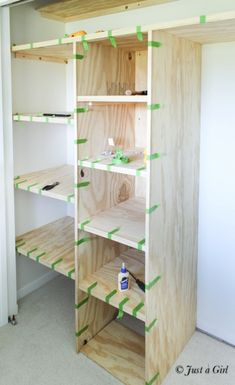 an unfinished closet with shelves and green tape on the bottom half of each shelving unit