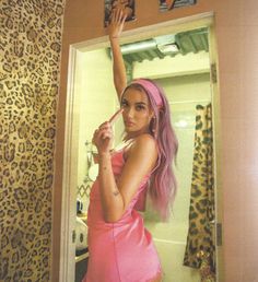 a woman with pink hair is taking a selfie in front of a leopard print wallpaper